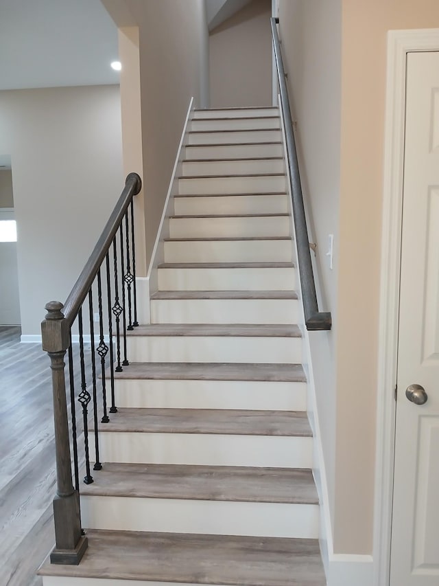 staircase with wood finished floors and baseboards