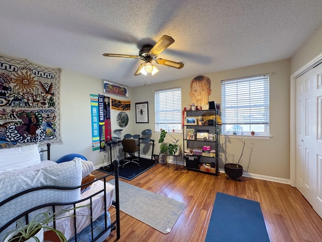 exercise area with a wealth of natural light, baseboards, a ceiling fan, and wood finished floors