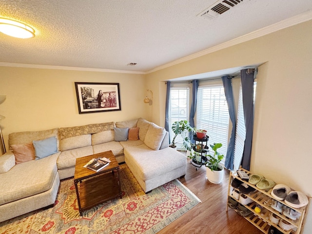 living area with visible vents, crown molding, a textured ceiling, and wood finished floors