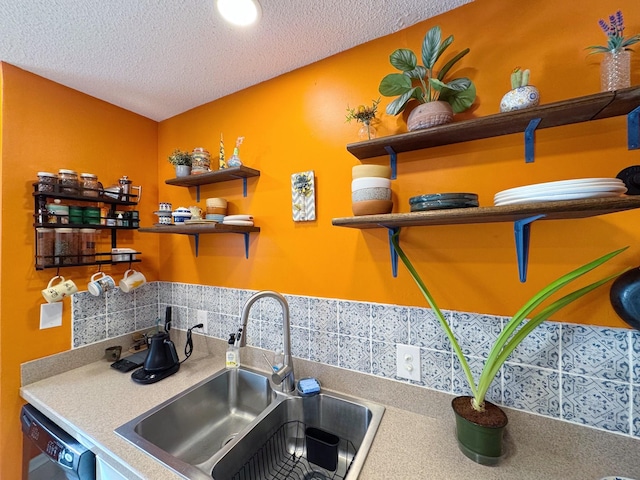 kitchen featuring a textured ceiling, dishwashing machine, open shelves, and a sink