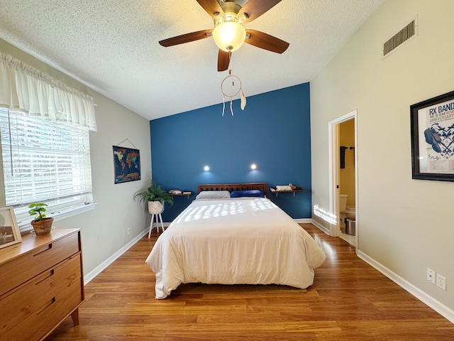 bedroom featuring lofted ceiling, a textured ceiling, visible vents, and wood finished floors