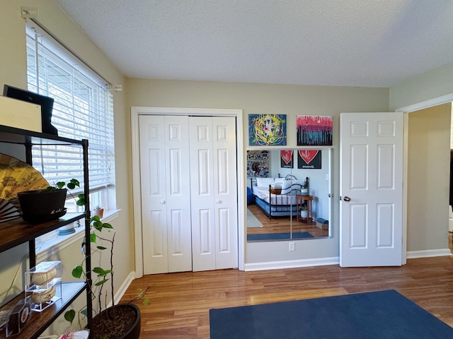 bedroom with a textured ceiling, a closet, baseboards, and wood finished floors