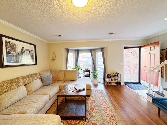 living area with visible vents, crown molding, stairway, and wood finished floors