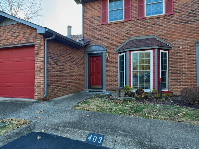 property entrance with a garage and brick siding