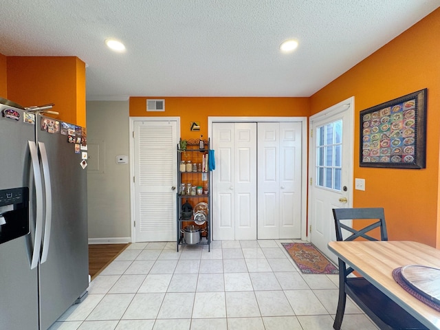 kitchen with light tile patterned floors, recessed lighting, visible vents, a textured ceiling, and stainless steel fridge