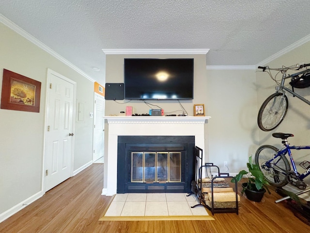 interior details featuring a fireplace with flush hearth, ornamental molding, a textured ceiling, and wood finished floors