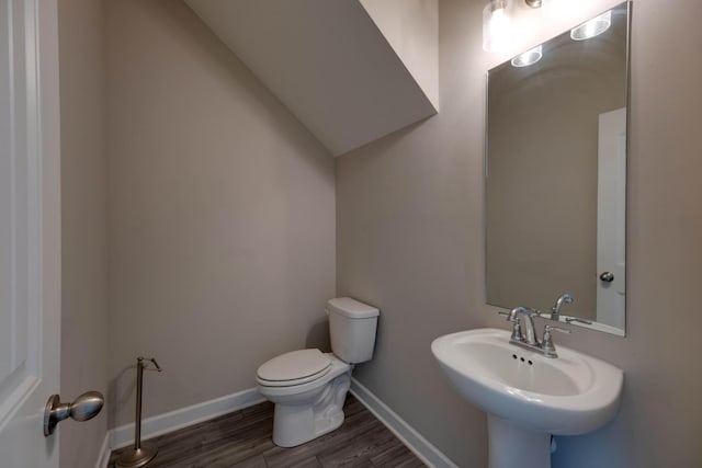 half bathroom with a sink, wood finished floors, toilet, and baseboards