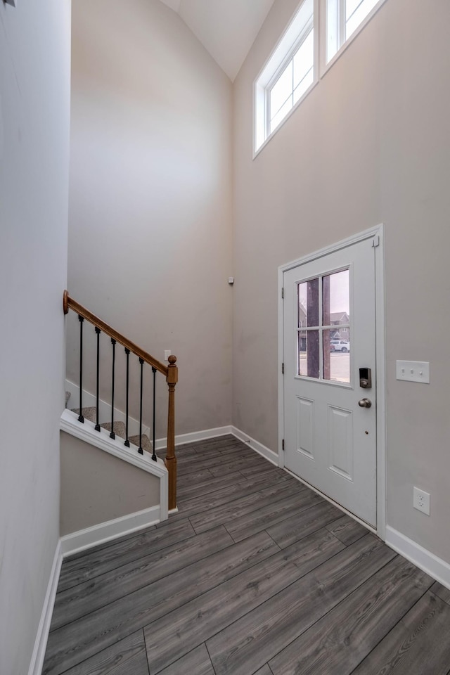 foyer featuring high vaulted ceiling, stairs, baseboards, and wood finished floors