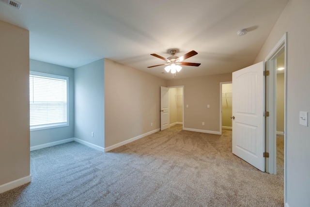 unfurnished bedroom with a spacious closet, carpet flooring, visible vents, and baseboards