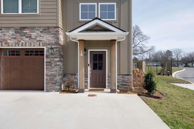 entrance to property with a garage, stone siding, and board and batten siding