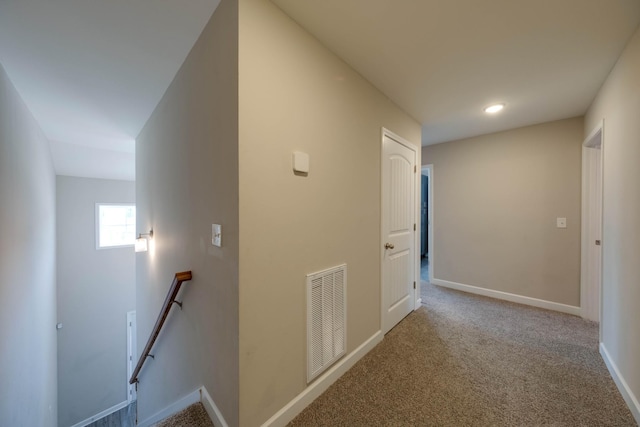 corridor with carpet flooring, visible vents, baseboards, and an upstairs landing