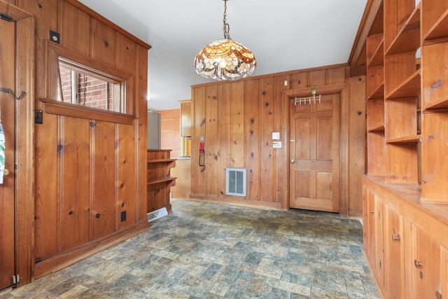 entryway with stone finish floor, visible vents, and wood walls