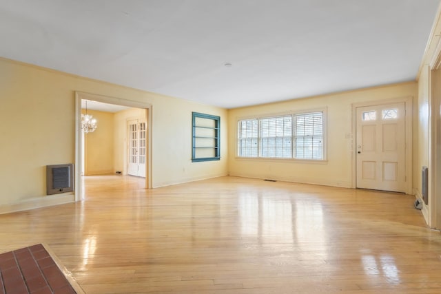 unfurnished living room featuring light wood-style flooring, visible vents, a chandelier, and baseboards