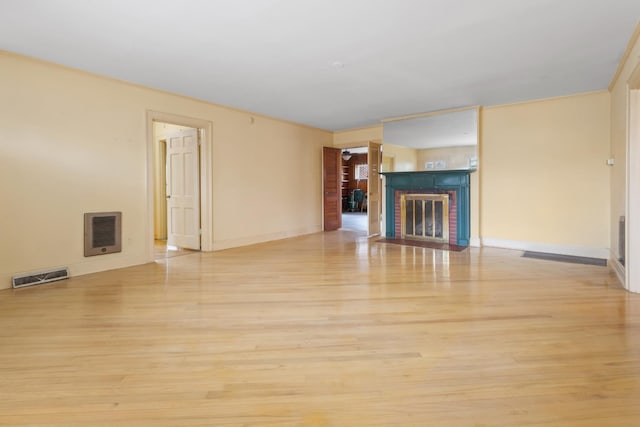 unfurnished living room with light wood finished floors, a fireplace, visible vents, and baseboards