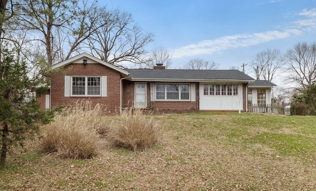 ranch-style home with a shingled roof, brick siding, a chimney, and a front lawn