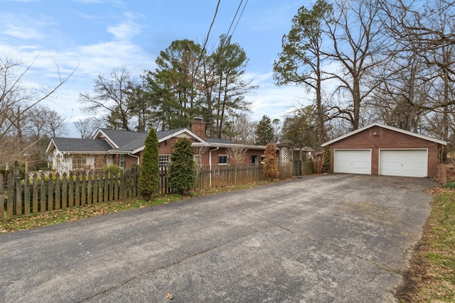 view of home's exterior featuring a fenced front yard, brick siding, a detached garage, a chimney, and an outdoor structure