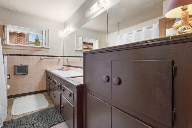 bathroom with wainscoting, toilet, tile patterned flooring, vanity, and tile walls