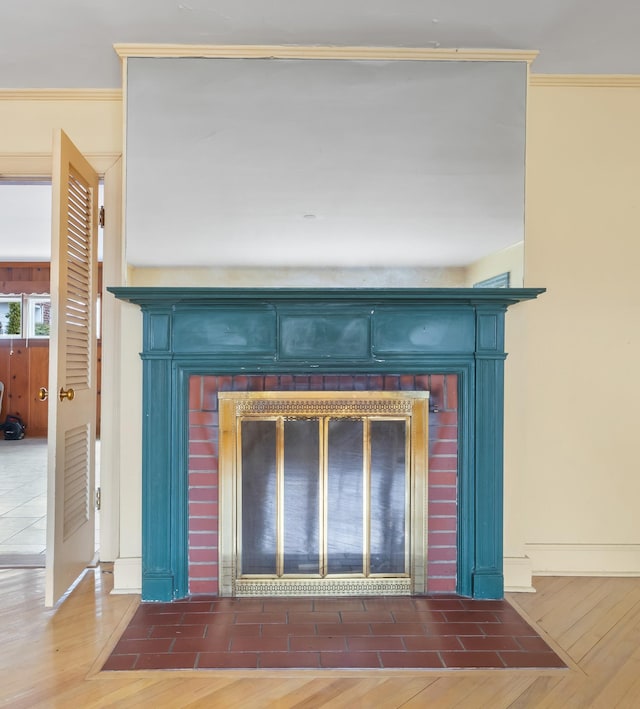 details with a brick fireplace, crown molding, and wood finished floors