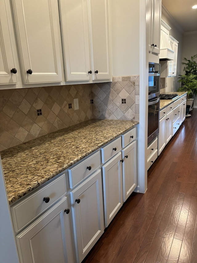 kitchen featuring dark wood-type flooring, backsplash, cooktop, and white cabinetry