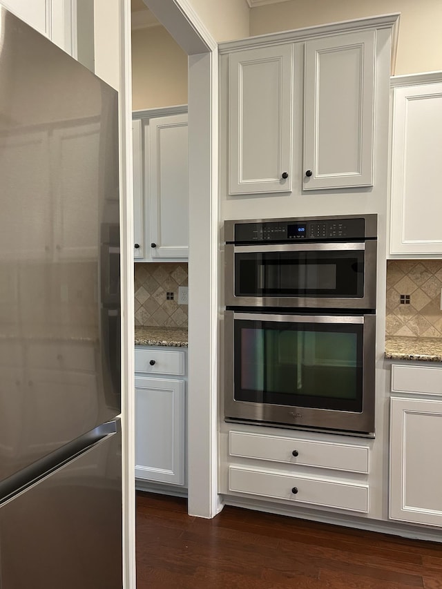 1012 Wooden Gate Dr, Franklin, TN 37064 - kitchen with stainless steel appliances, backsplash, dark wood-type flooring, light stone counters, and white cabinetry