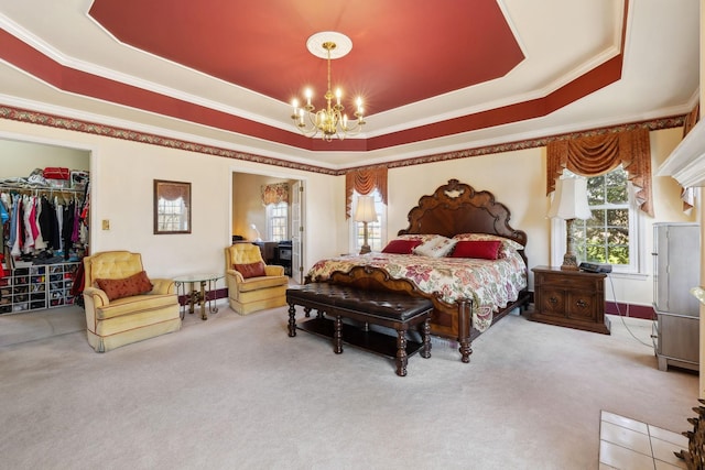 carpeted bedroom featuring ornamental molding, a raised ceiling, a spacious closet, and an inviting chandelier