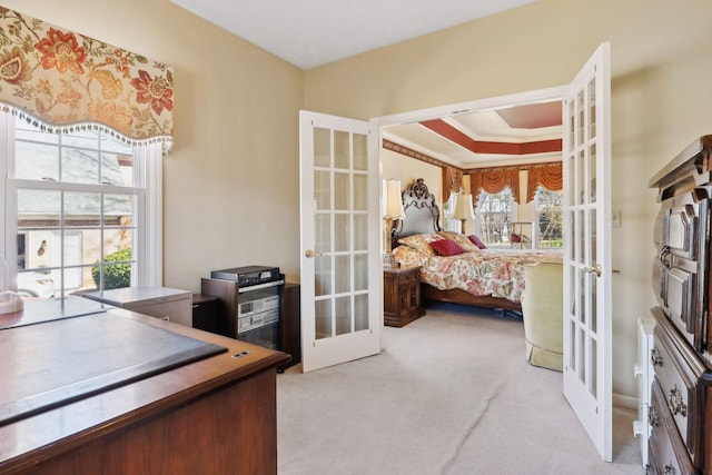 carpeted office space featuring a tray ceiling, french doors, and crown molding