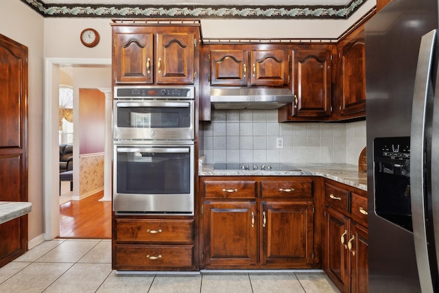 kitchen featuring stainless steel appliances, light tile patterned flooring, backsplash, and under cabinet range hood