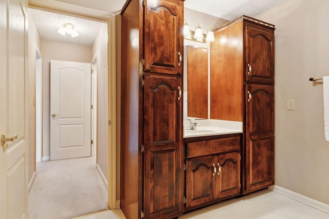 bathroom featuring baseboards, a textured ceiling, and vanity