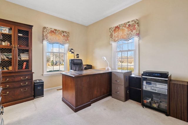 office space featuring baseboards, a healthy amount of sunlight, and light colored carpet