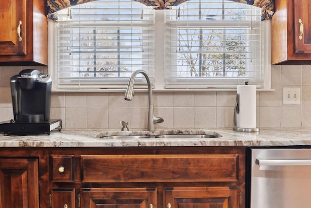 kitchen featuring decorative backsplash, a sink, light stone counters, and stainless steel dishwasher