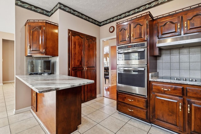 kitchen featuring light tile patterned floors, double oven, black electric cooktop, and under cabinet range hood