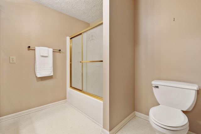 full bath with a textured ceiling, toilet, baseboards, combined bath / shower with glass door, and tile patterned floors