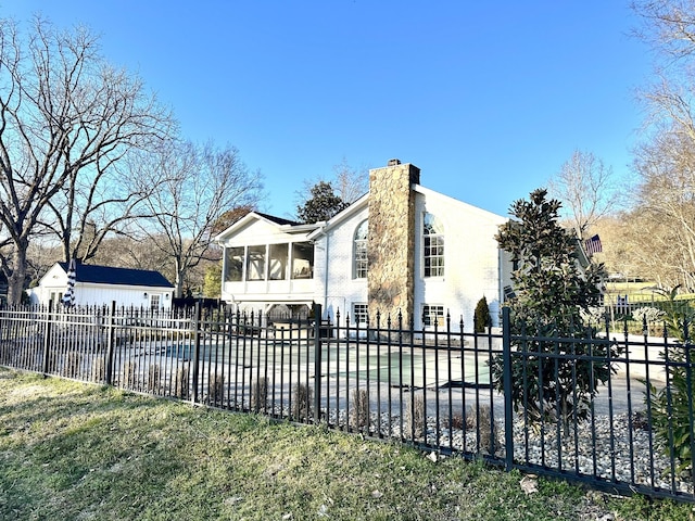 exterior space with a chimney, fence private yard, and a sunroom