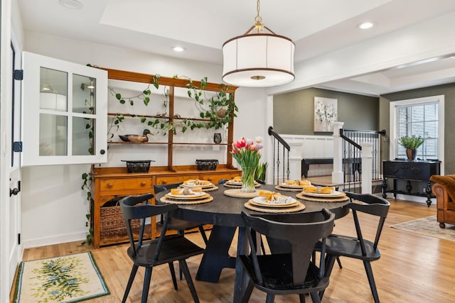 dining room with stairway, a raised ceiling, light wood-style flooring, and recessed lighting