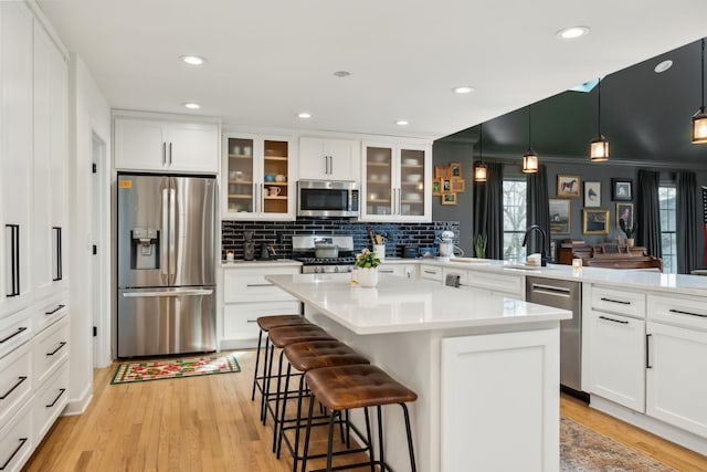 kitchen with a peninsula, light wood-type flooring, a breakfast bar area, and stainless steel appliances