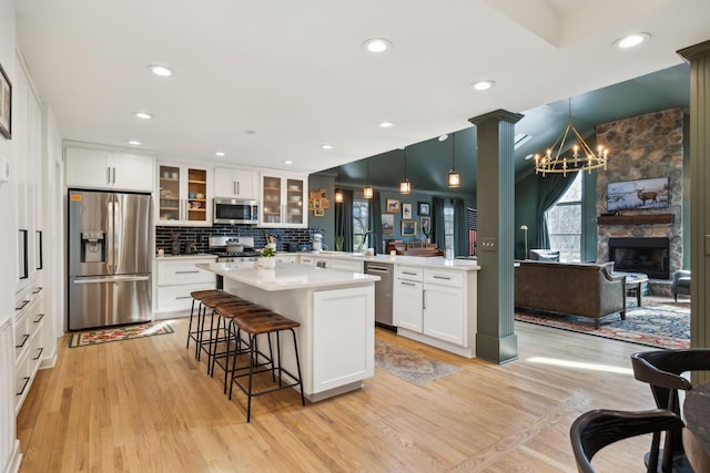 kitchen with light wood finished floors, a breakfast bar area, stainless steel appliances, an inviting chandelier, and a peninsula