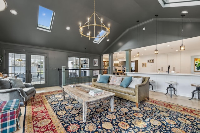 living area featuring a skylight, decorative columns, light wood-style flooring, crown molding, and french doors