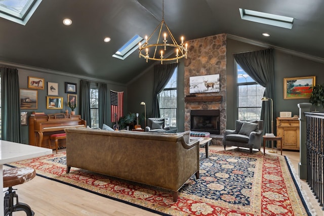 living area featuring a wealth of natural light, wood finished floors, crown molding, and a stone fireplace