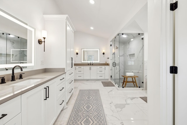 full bath with lofted ceiling, two vanities, a sink, marble finish floor, and a marble finish shower