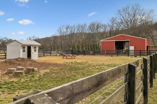 view of yard featuring a rural view, an exterior structure, and an outdoor structure