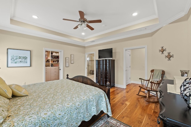 bedroom featuring ornamental molding, a tray ceiling, baseboards, and wood finished floors