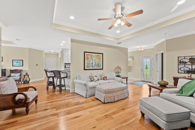 living room with ornamental molding, recessed lighting, light wood-style flooring, and baseboards