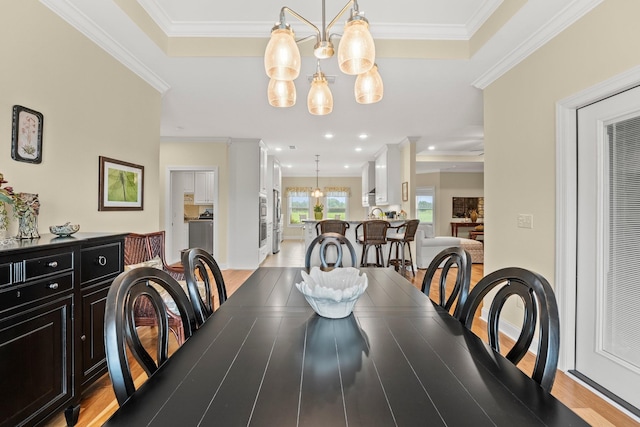 dining space with a chandelier, ornamental molding, and light wood finished floors