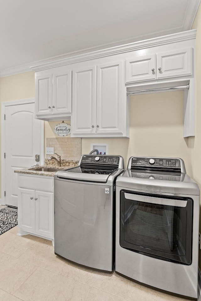 laundry area featuring washing machine and dryer, a sink, cabinet space, and crown molding