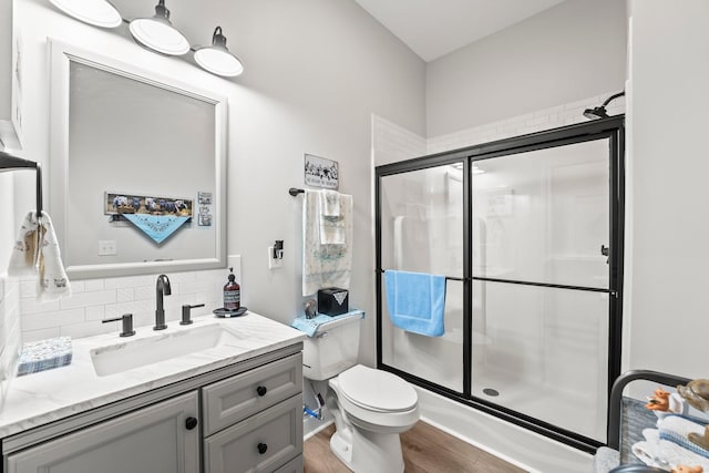 full bath featuring a stall shower, decorative backsplash, toilet, wood finished floors, and vanity