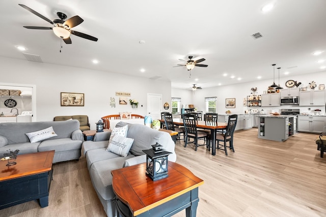 living room featuring washer / dryer, recessed lighting, visible vents, and light wood-style floors