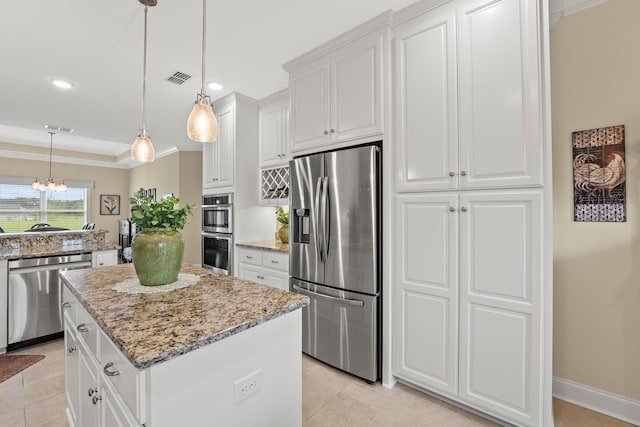 kitchen featuring visible vents, white cabinets, a kitchen island, light stone countertops, and stainless steel appliances