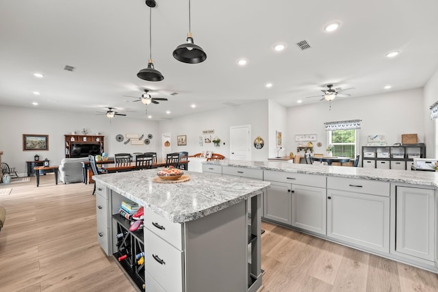 kitchen with gray cabinetry, light wood-style floors, visible vents, and a center island