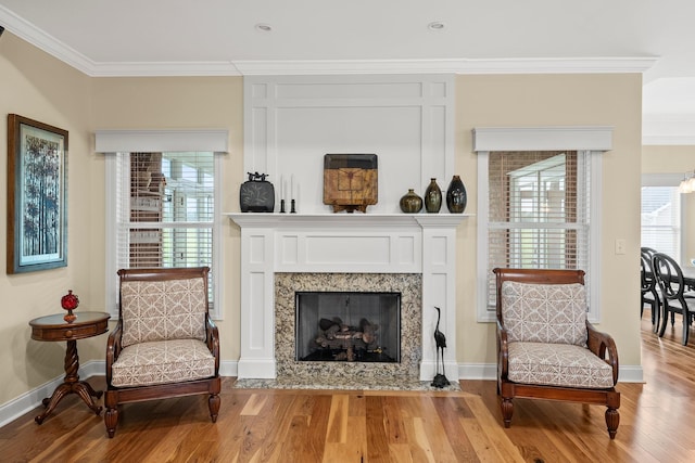 sitting room with baseboards, a fireplace, ornamental molding, and wood finished floors