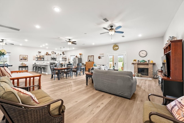 living room featuring light wood finished floors, visible vents, and french doors